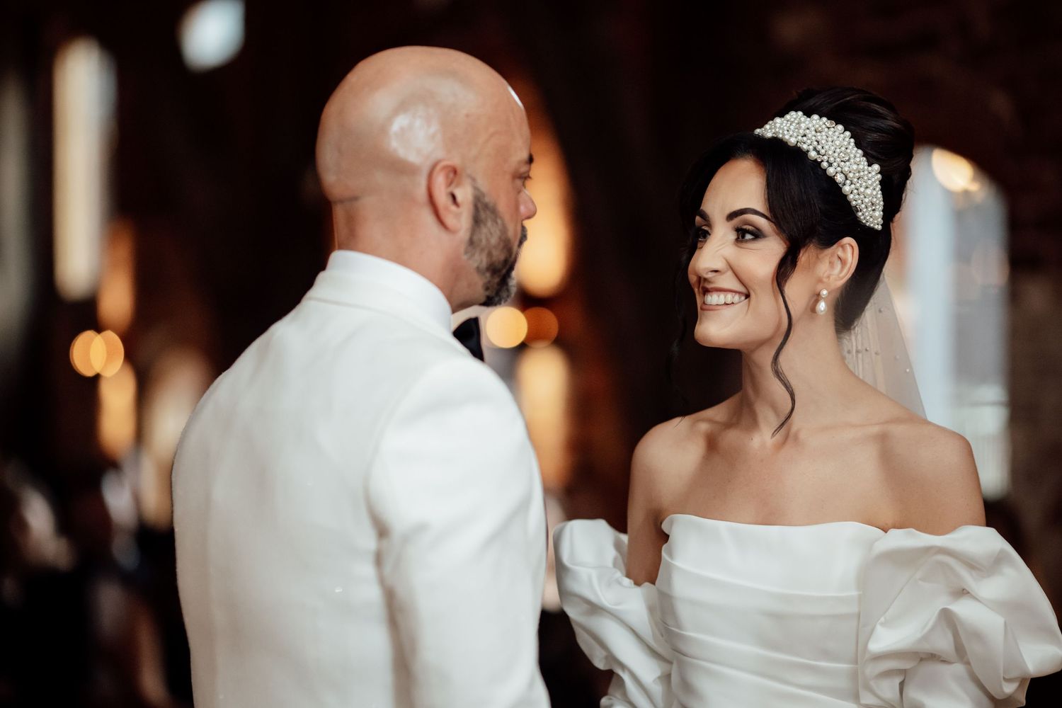 Elegant wedding couple shares intimate moments in formal attire against a warm glowing background.