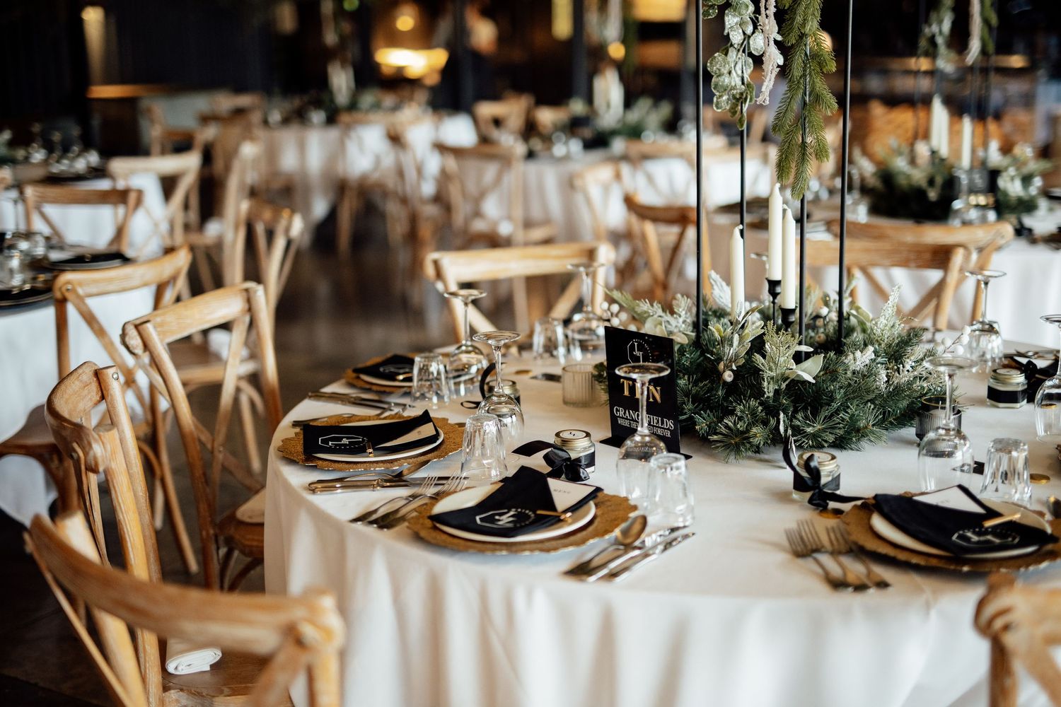 Modern wedding table settings with gold chargers, black napkins and delicate floral centerpieces.