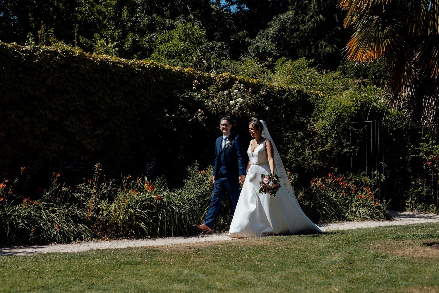 Wedding ceremony setup in a lush garden with white chairs and floral decorations.
