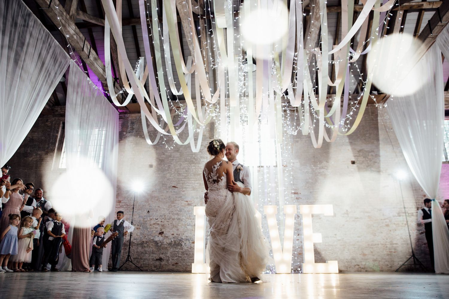 Wedding reception venue decorated with elegant white drapes and chandeliers.