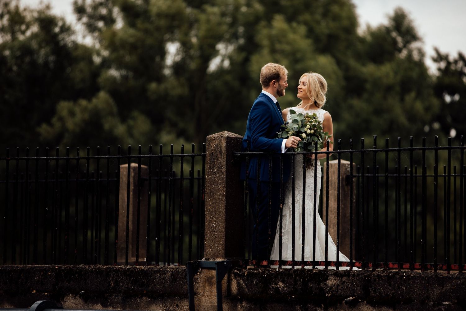 Romantic wedding photography session along iron fence at sunset.