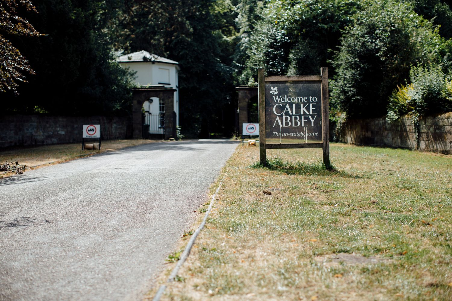 Rural country road leading to a wedding venue surrounded by green trees.