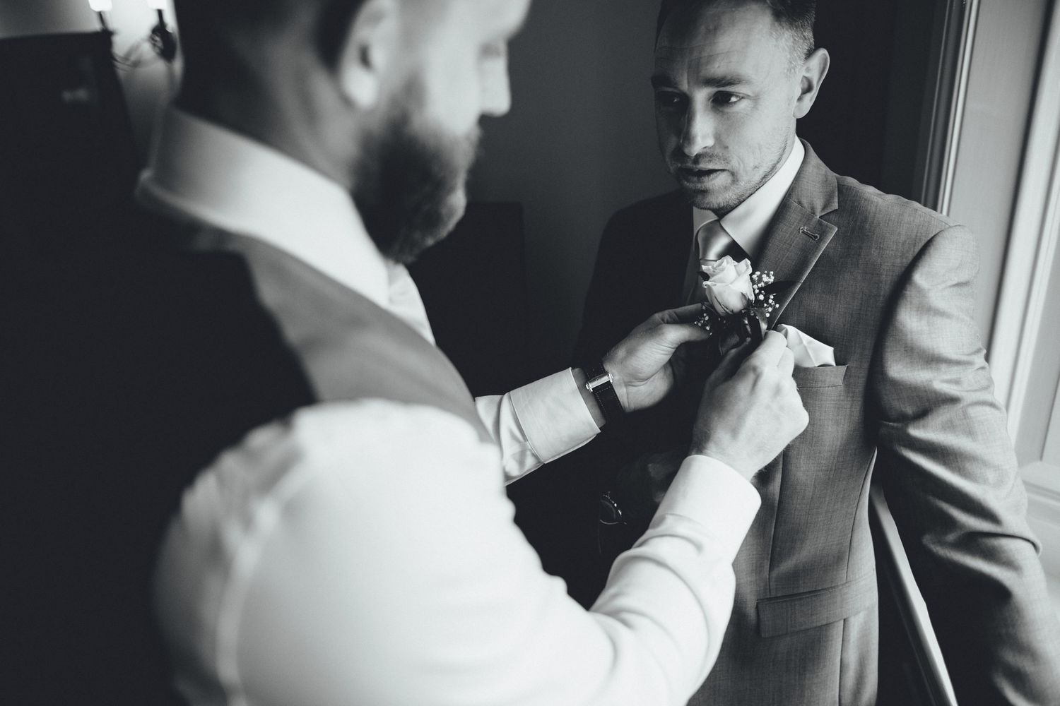 Black and white photos of wedding preparations with people getting dressed in formal attire.