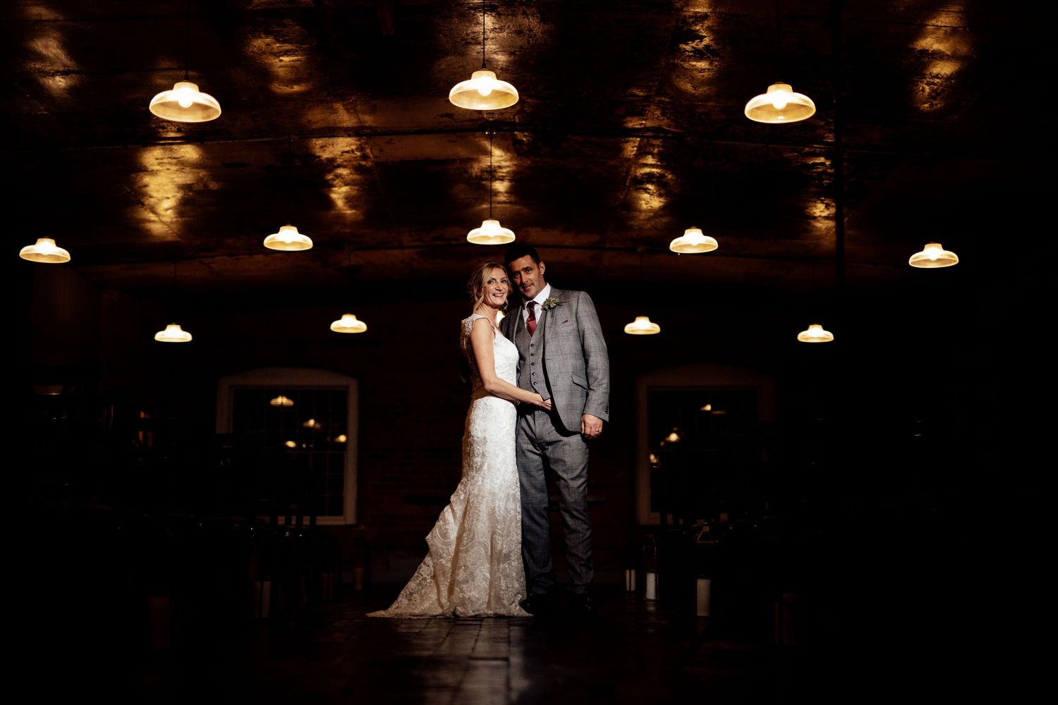 A romantic wedding scene in a rustic brick venue with pendant lighting creating a warm ambiance.
