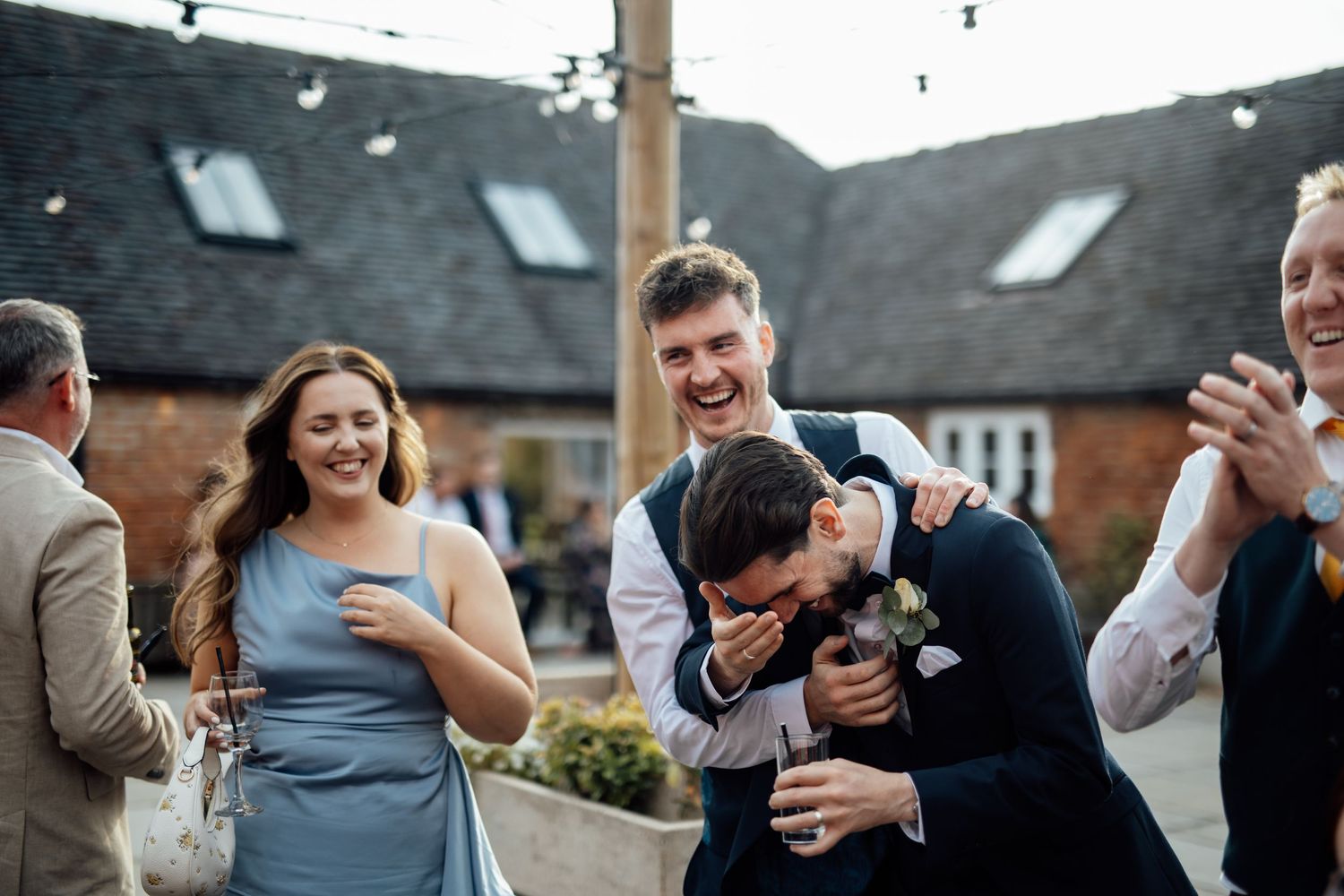 Wedding guests celebrate joyfully during an outdoor reception with confetti and laughter.