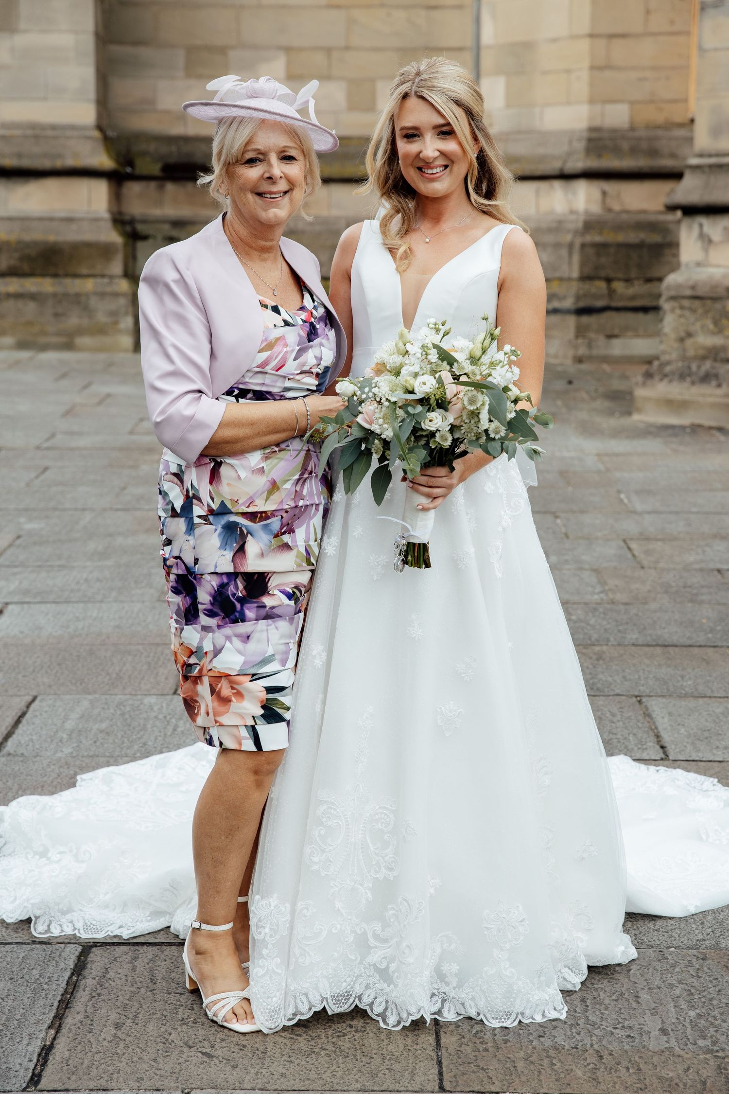 Beautiful white wedding dress with lace details and flowing train on stone steps.