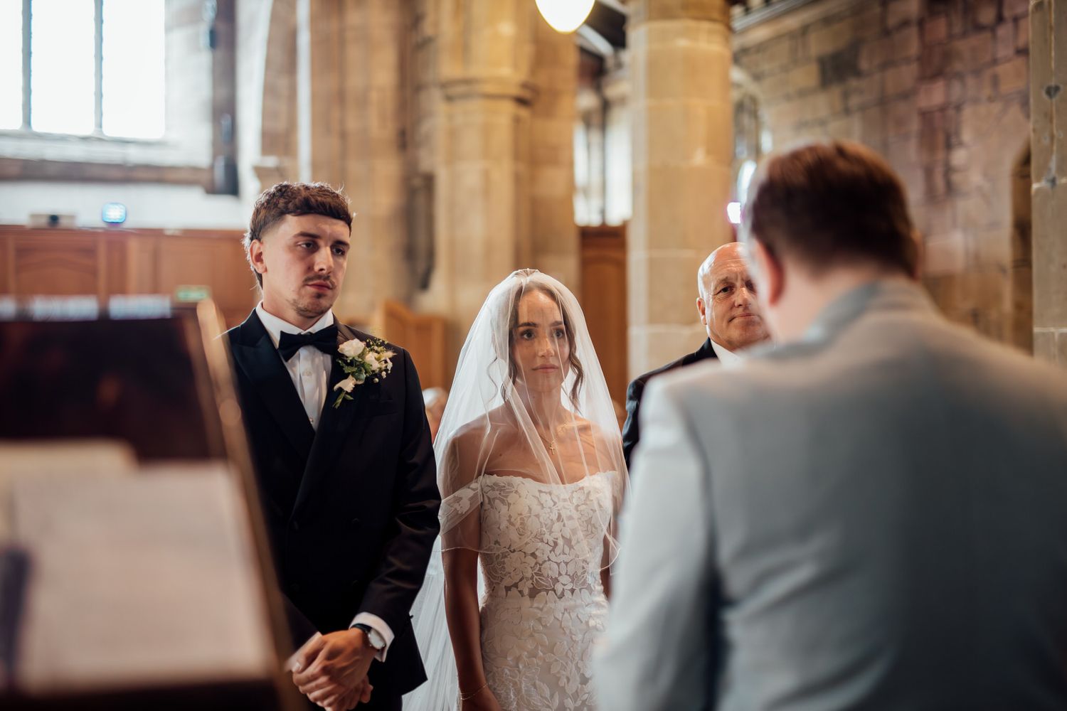 A wedding ceremony takes place inside a historic church with stone archways and columns.