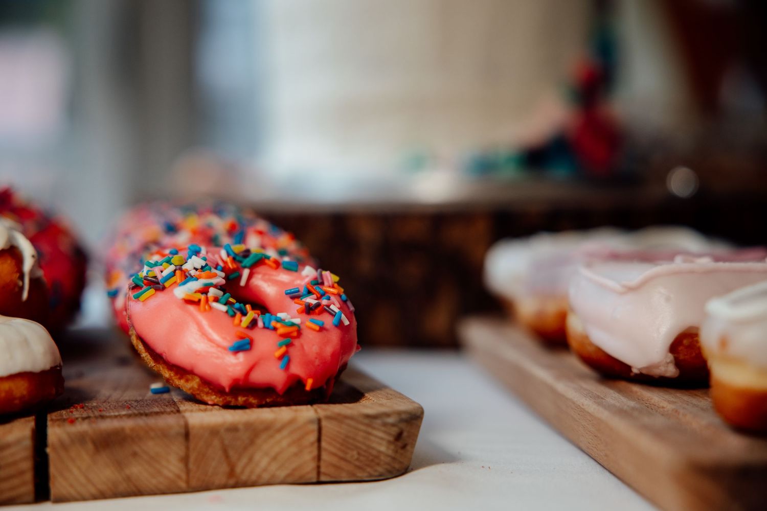 Colorful frosted donuts displayed on wooden serving boards.