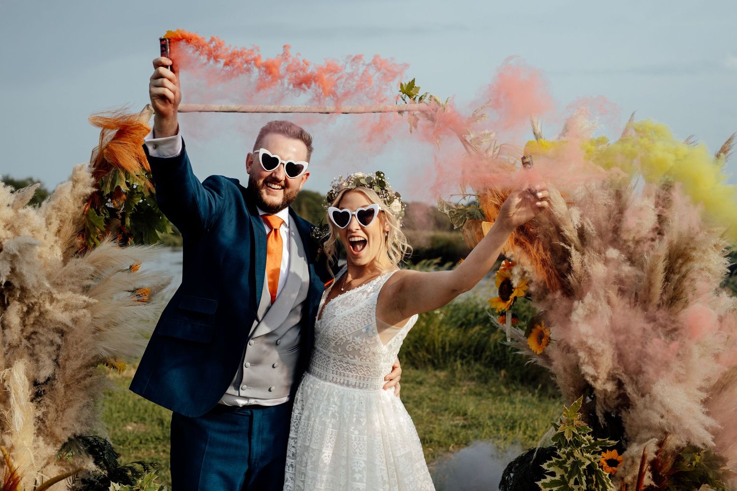 Couple celebrates with colorful smoke bombs in an outdoor wedding photoshoot.
