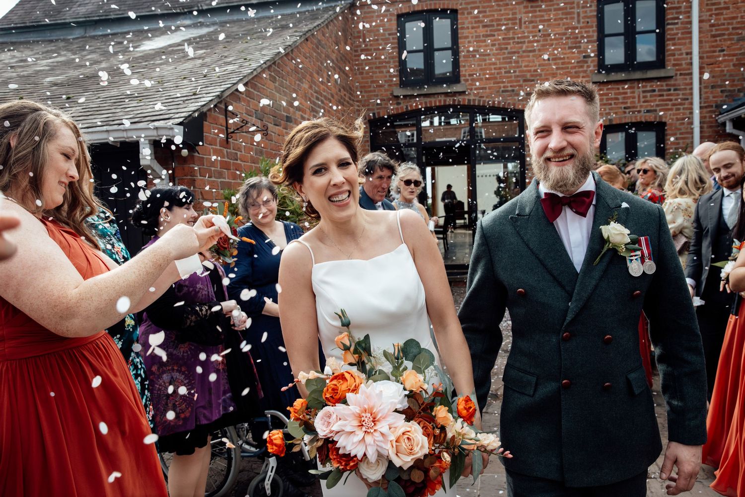 Wedding party celebration with confetti outside a brick building.