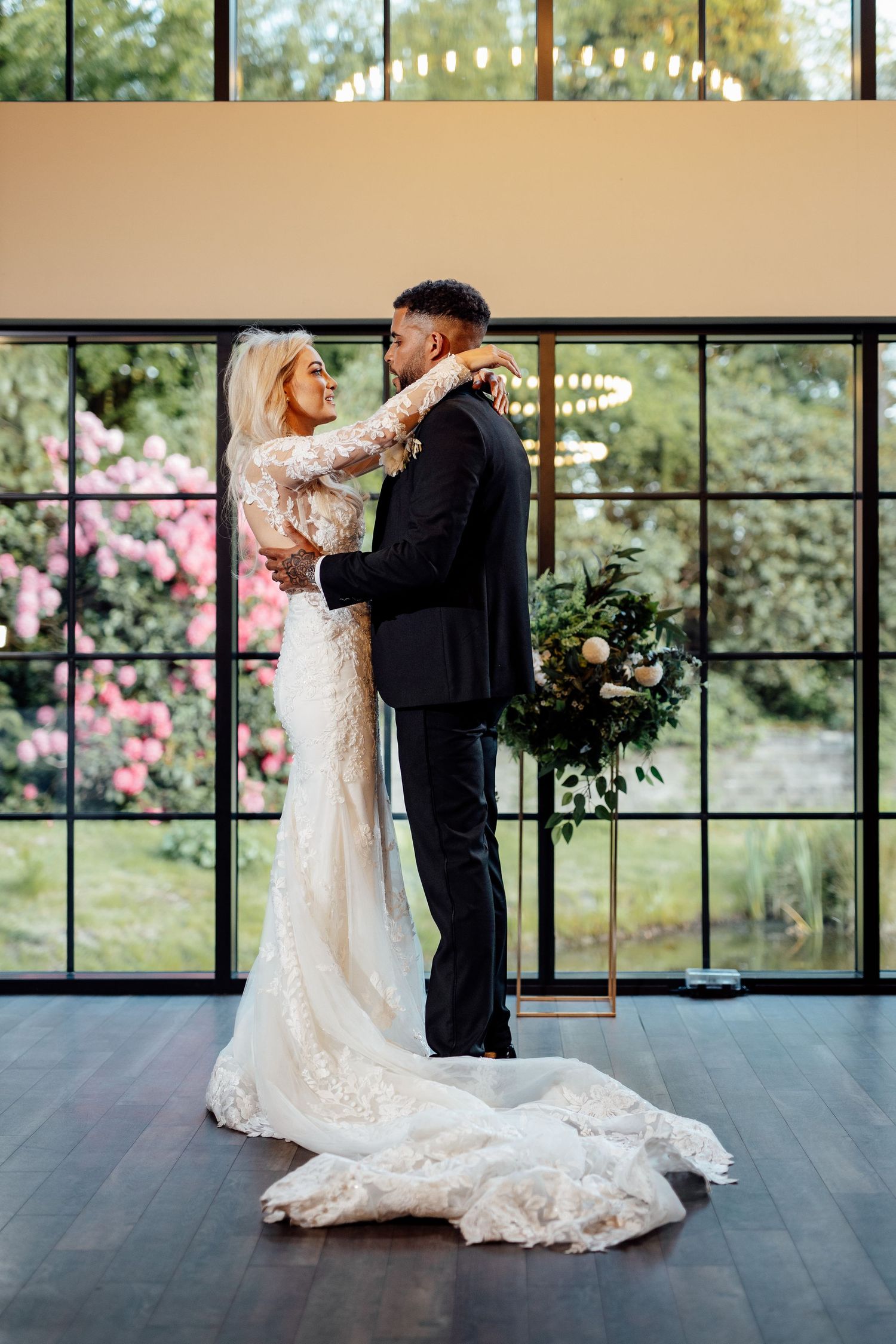 A couple shares their first dance in an elegant venue with floor-to-ceiling windows and natural light.