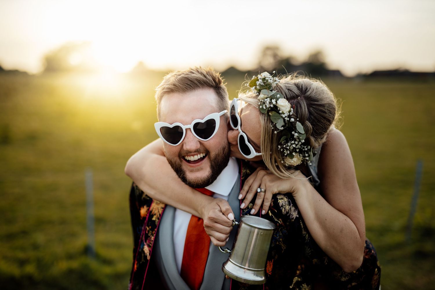 Wedding celebration at sunset with guests enjoying drinks and festivities outdoors.