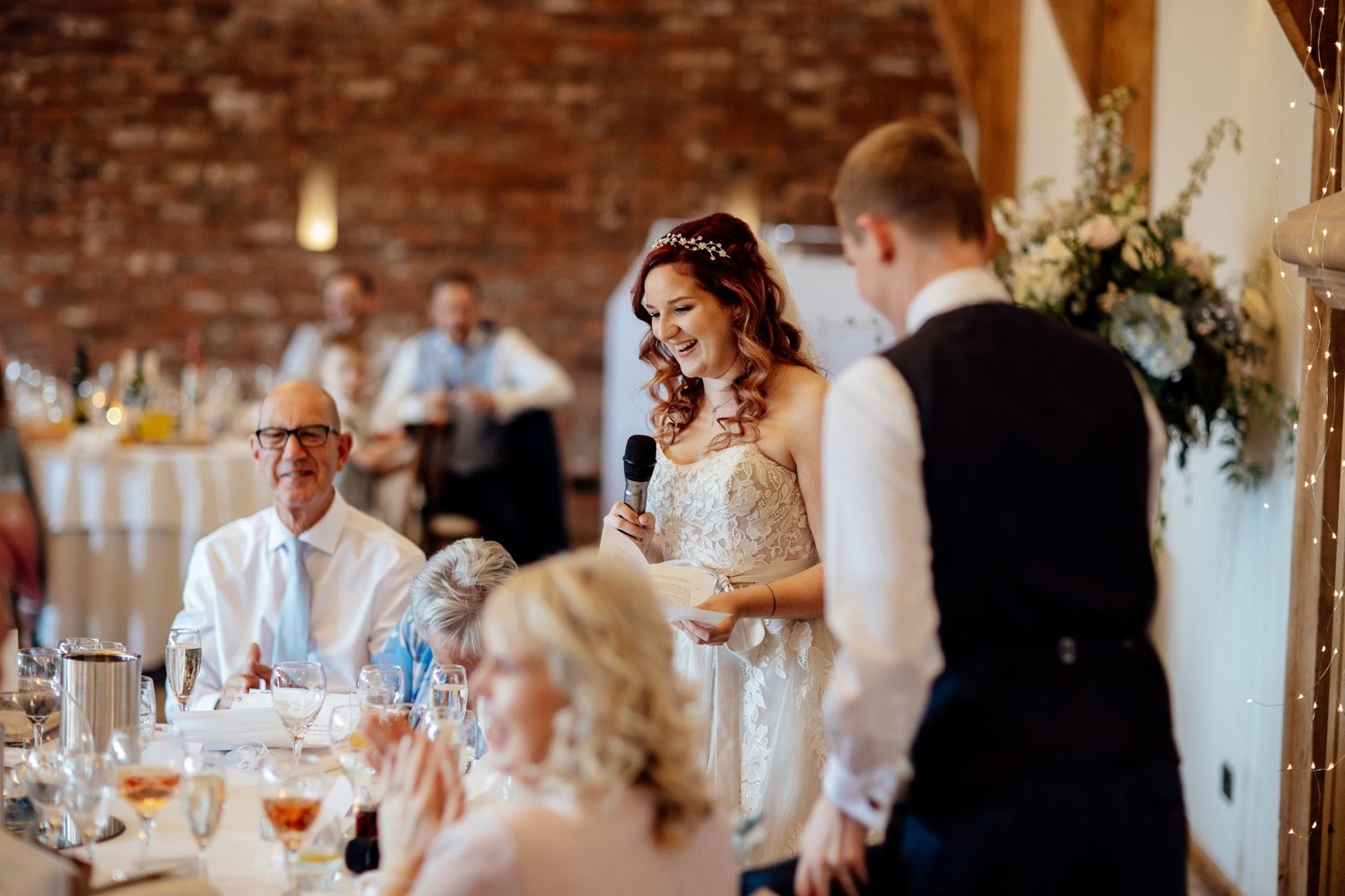 Wedding reception toast being given in a rustic venue with exposed brick walls.