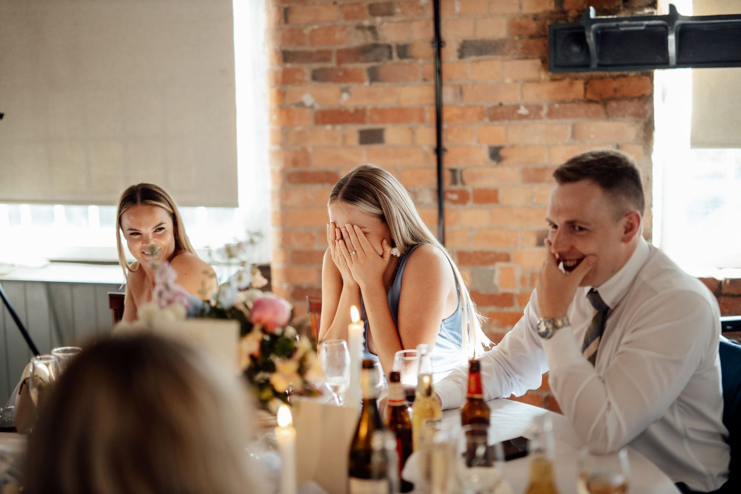 Wedding reception setup with brick walls and elegant table settings at a rustic venue.