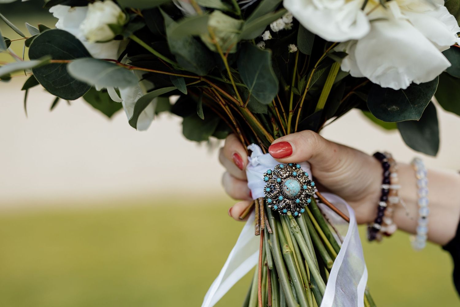 Close-up of white rose wedding bouquet with greenery accents.
