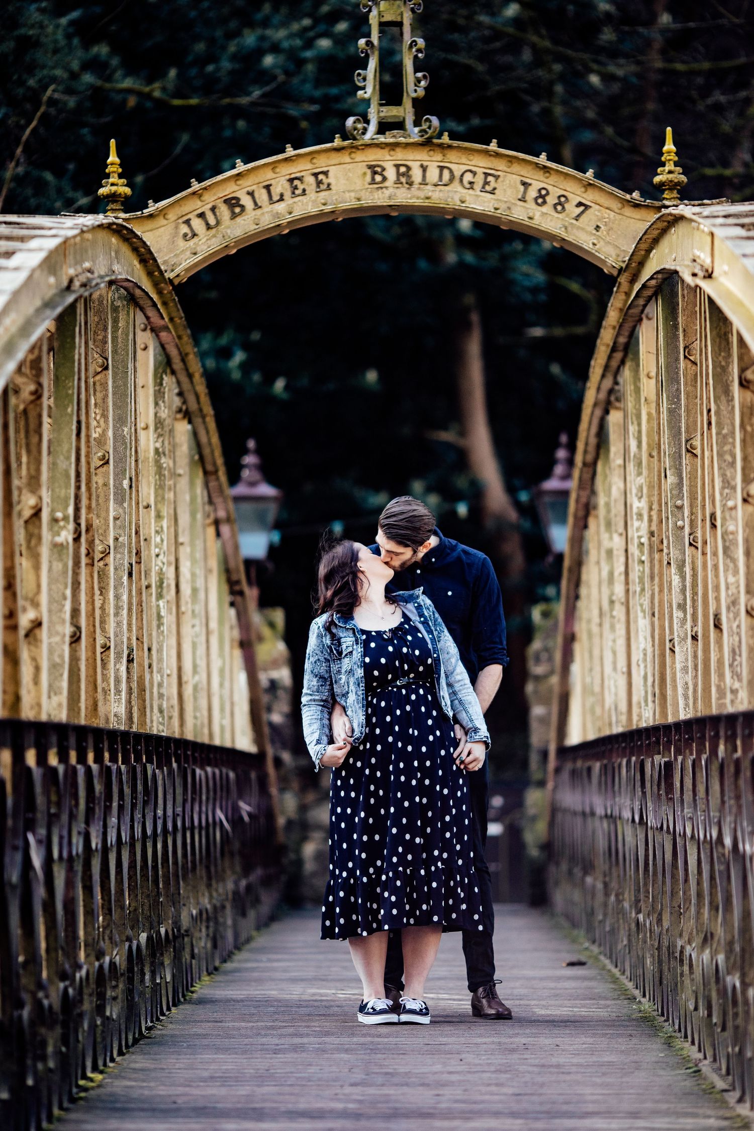 A couple stands on the historic Jubilee Bridge with ornate metalwork and arches.