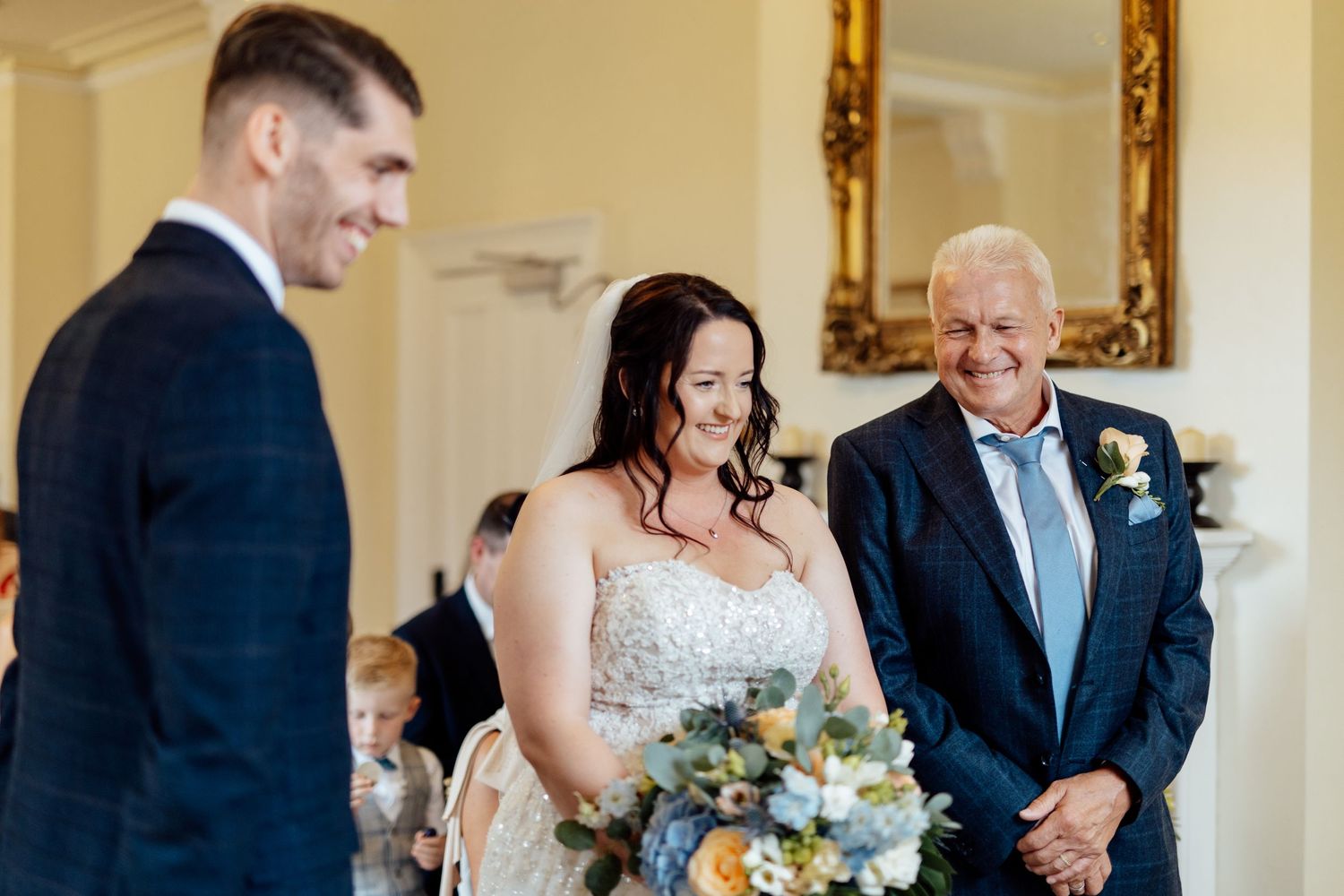 Wedding ceremony processional in an elegant ballroom with golden decor.