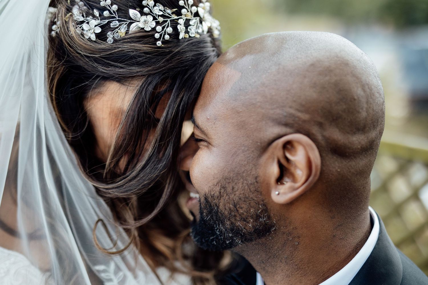 Close-up of a romantic moment between the bride and groom with baby's breath in her hair.