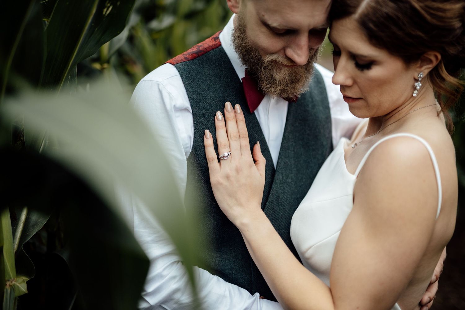 Intimate wedding couple moment captured in garden setting.