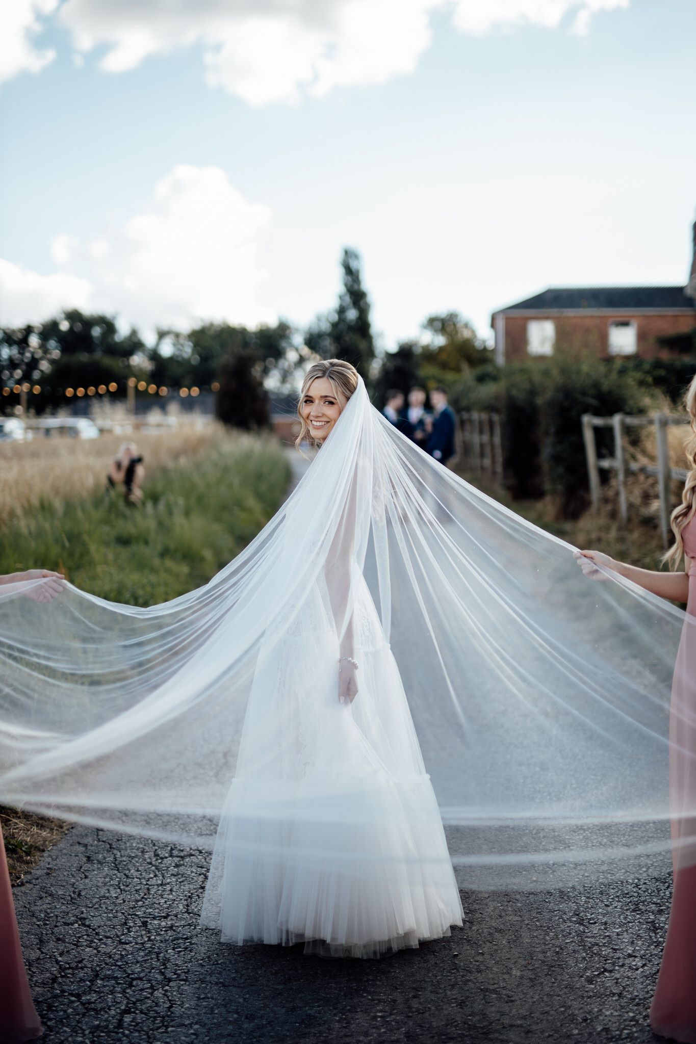 Dramatic shot of flowing white wedding veil caught in breeze against countryside setting.