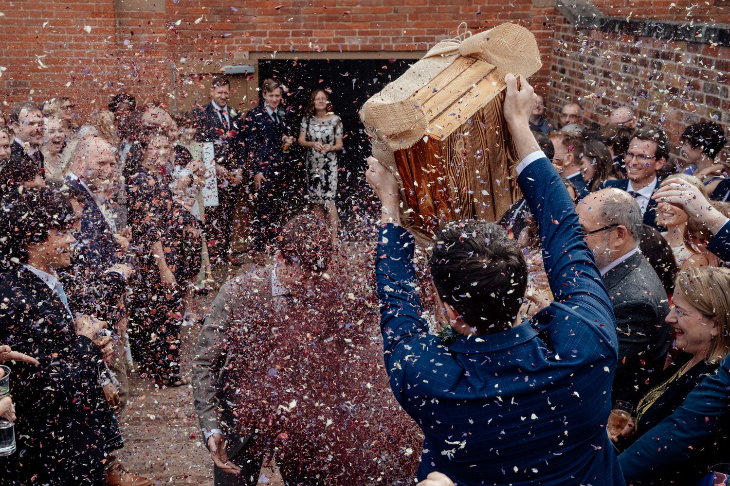 Guests celebrate with confetti at an outdoor brick venue.