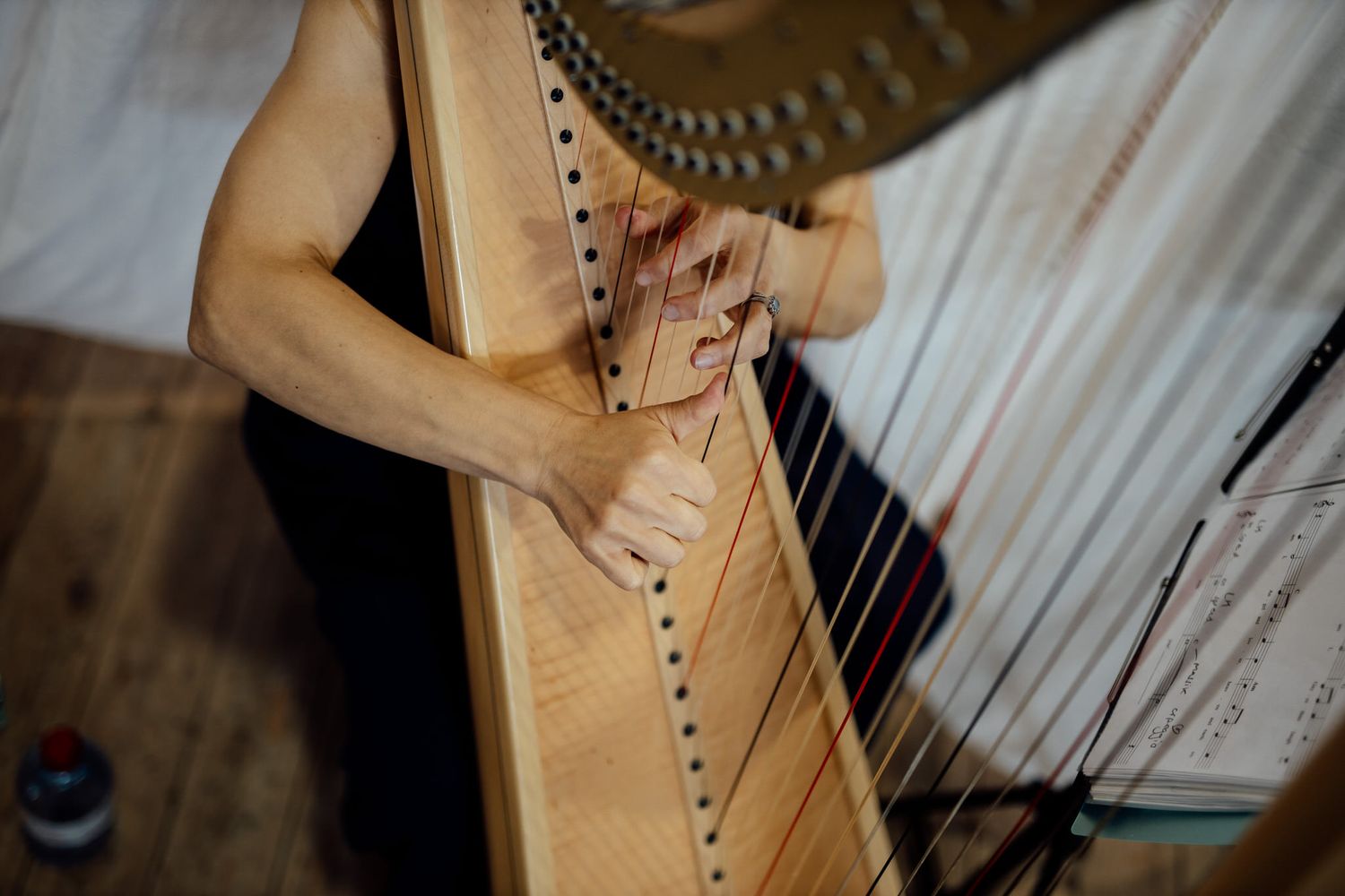 Close-up of an elegant wooden harp being played at a wedding ceremony.