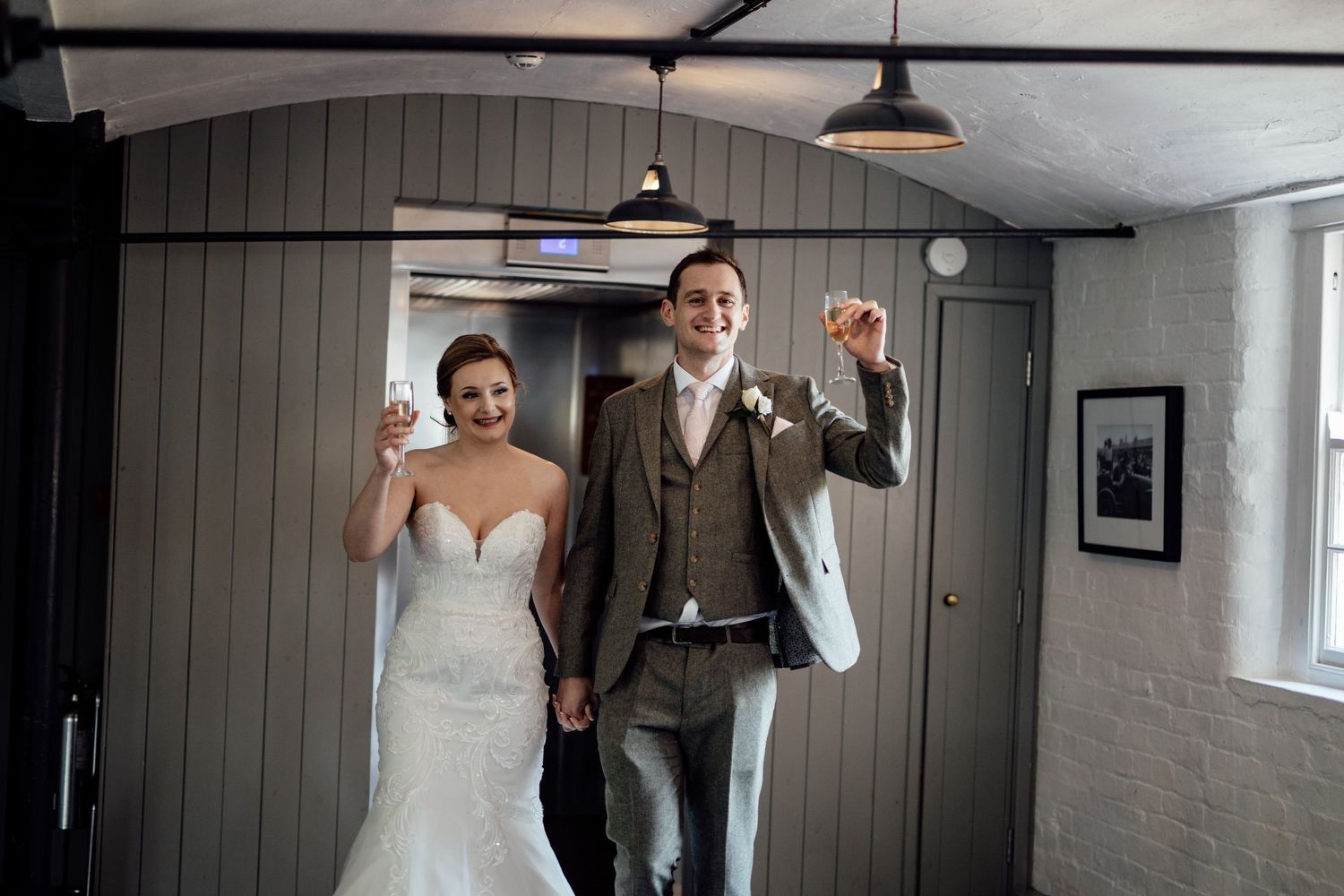 Wedding party members share joyful moments in a rustic indoor setting.
