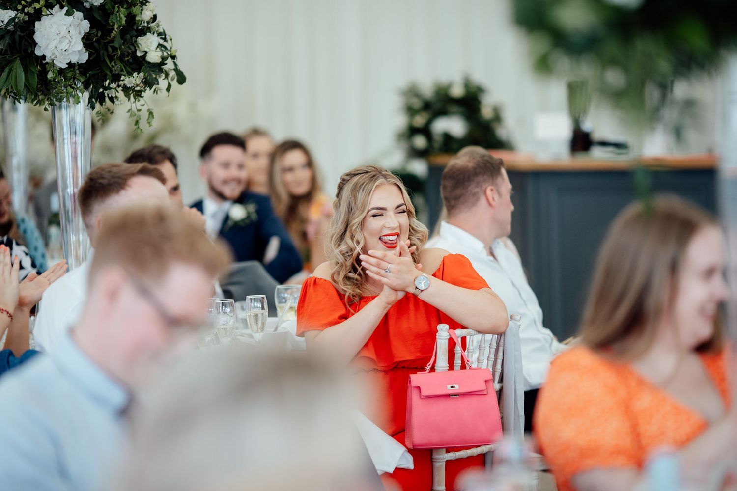 Wedding guests in bright attire mingling at an indoor reception venue.