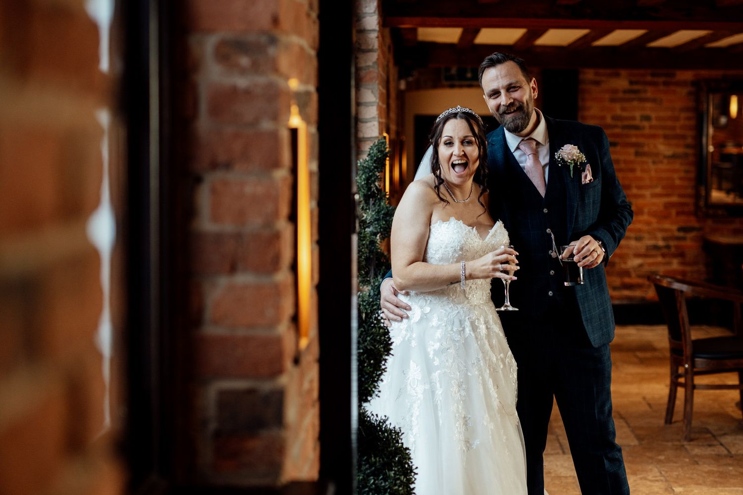 Wedding couple shares intimate moment in rustic brick venue interior.