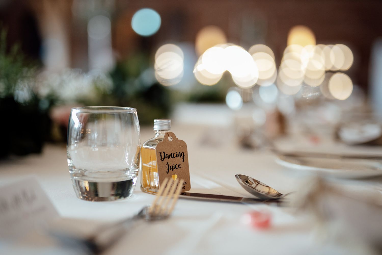 Elegant table setting with bokeh lights and glassware at wedding reception.