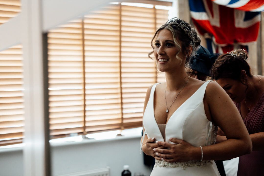 Indoor wedding preparation scene with natural window light filtering through blinds.