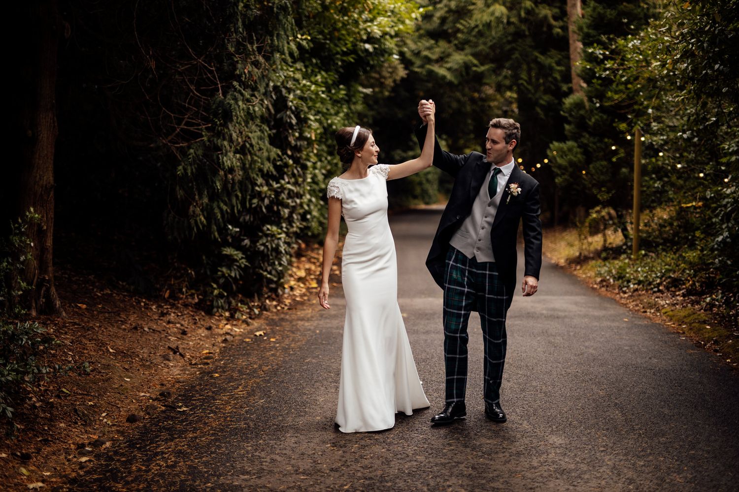 Wedding couple walking together on a scenic autumn path surrounded by trees.