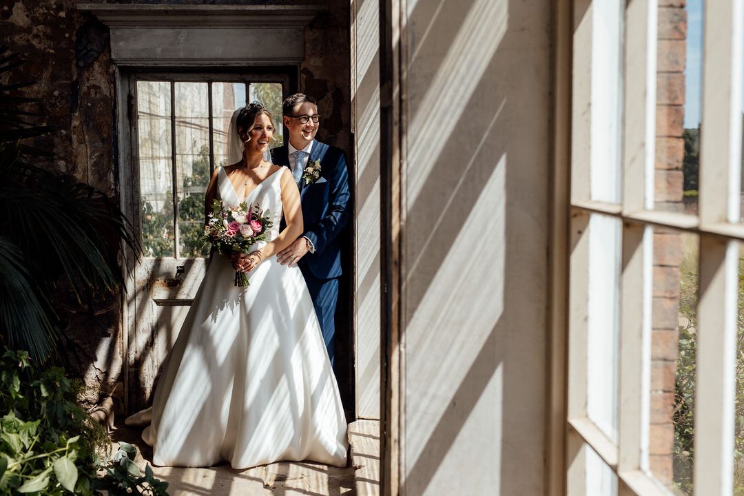 Elegant wedding photos captured in a sunlit corridor with architectural details.