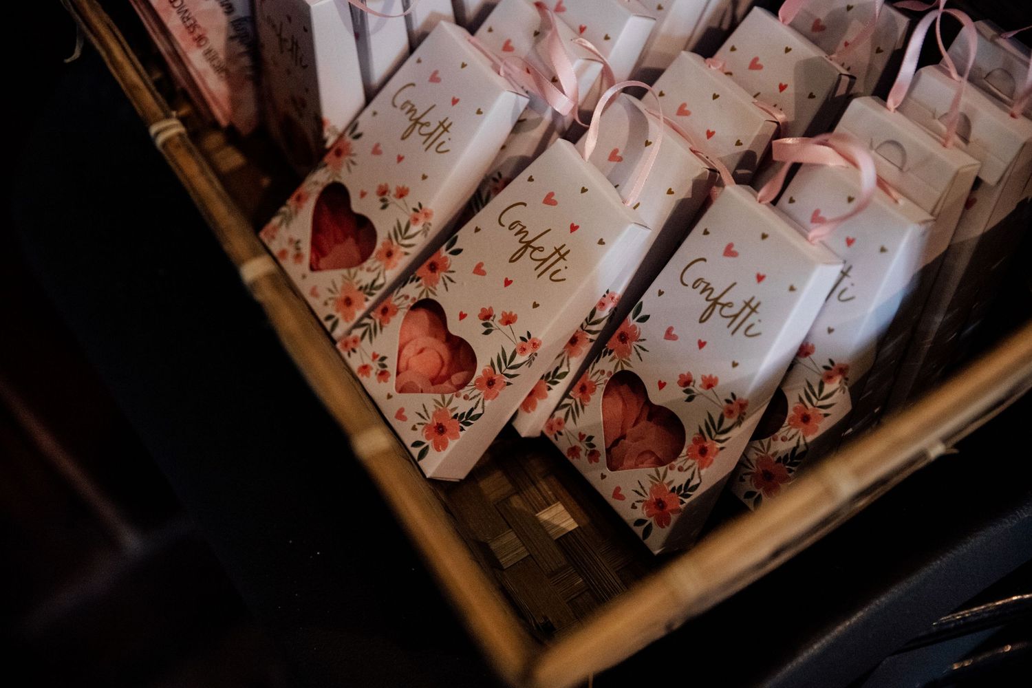 Wedding favor bags with heart designs arranged in a wooden basket.