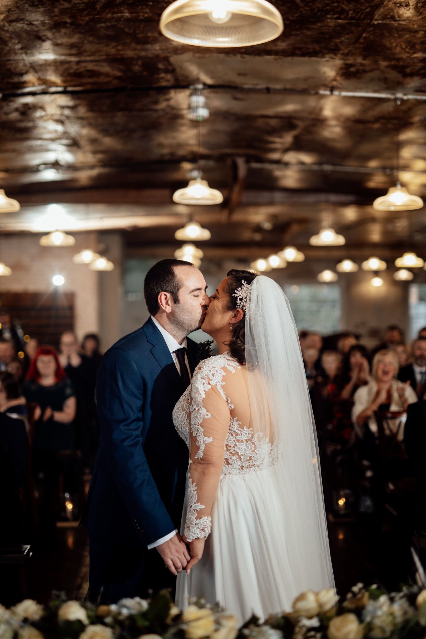 Wedding couple shares their first dance in an industrial-style venue with exposed ceiling beams.