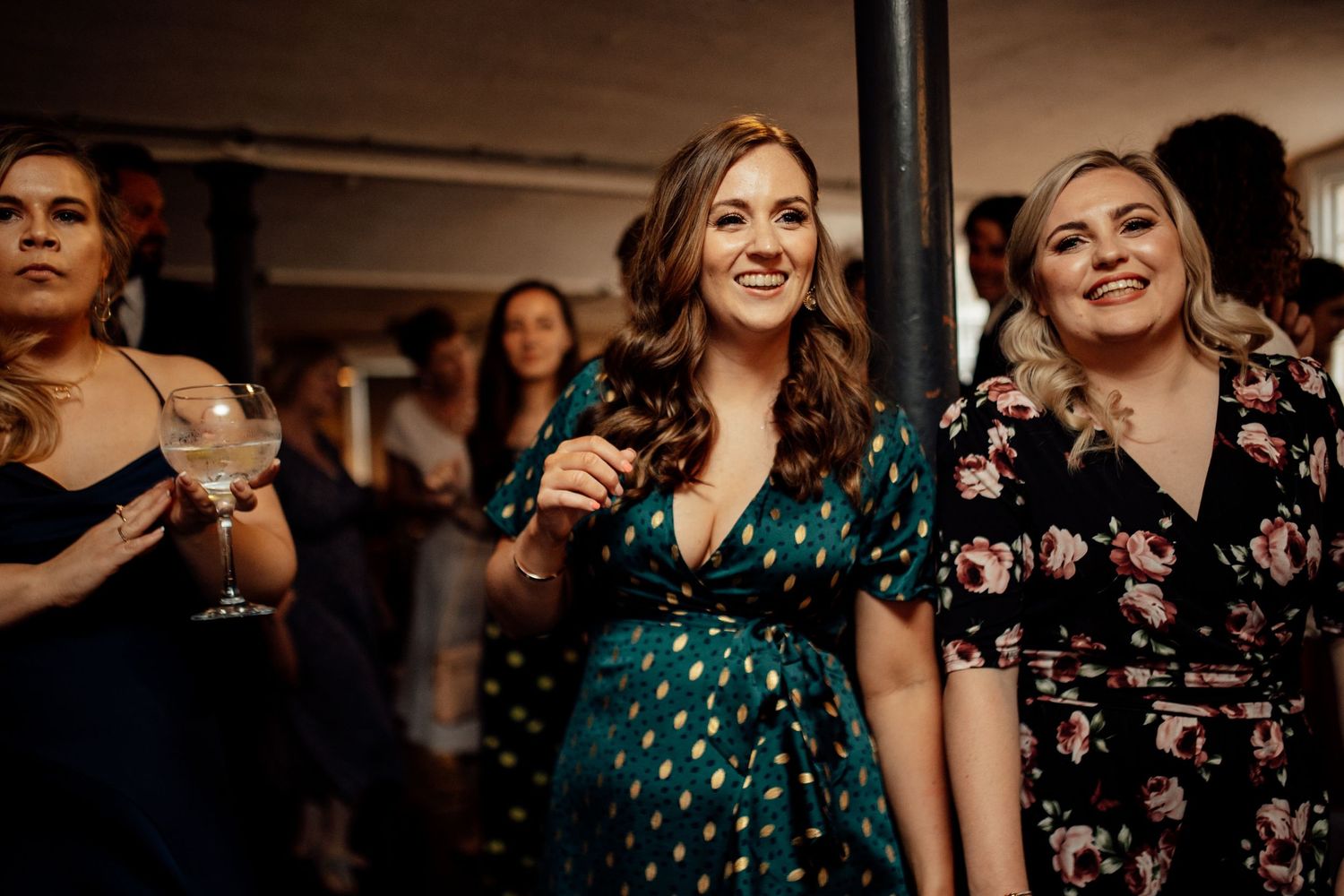 Wedding reception guests dance and celebrate in emerald green dresses.