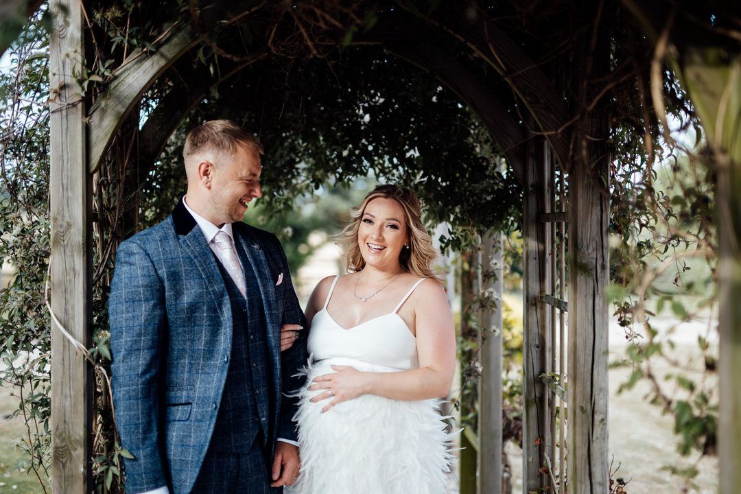 Romantic wedding portraits captured under an elegant garden archway with greenery.