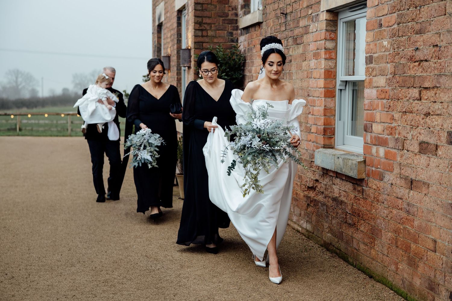 Wedding party walking outside a rustic brick building.