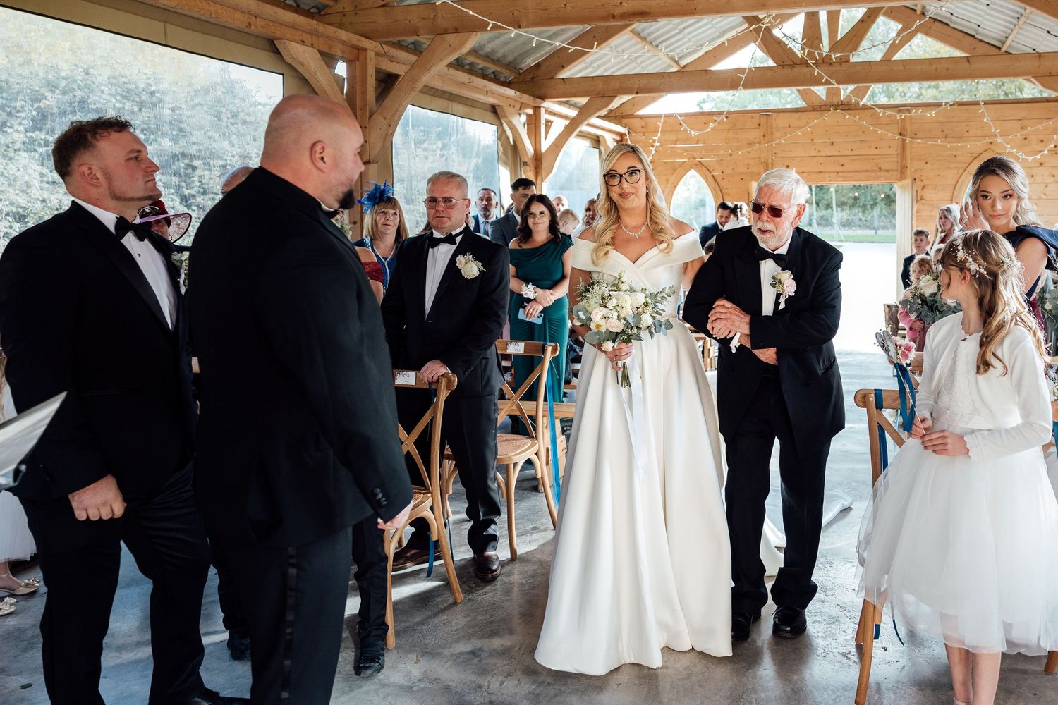 Wedding celebration under rustic wooden pavilion with exposed beams and natural lighting.