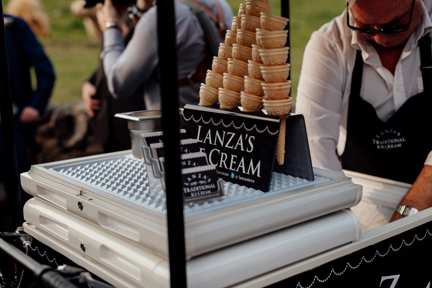 Ice cream station setup with multiple toppings and cones at an elegant event.