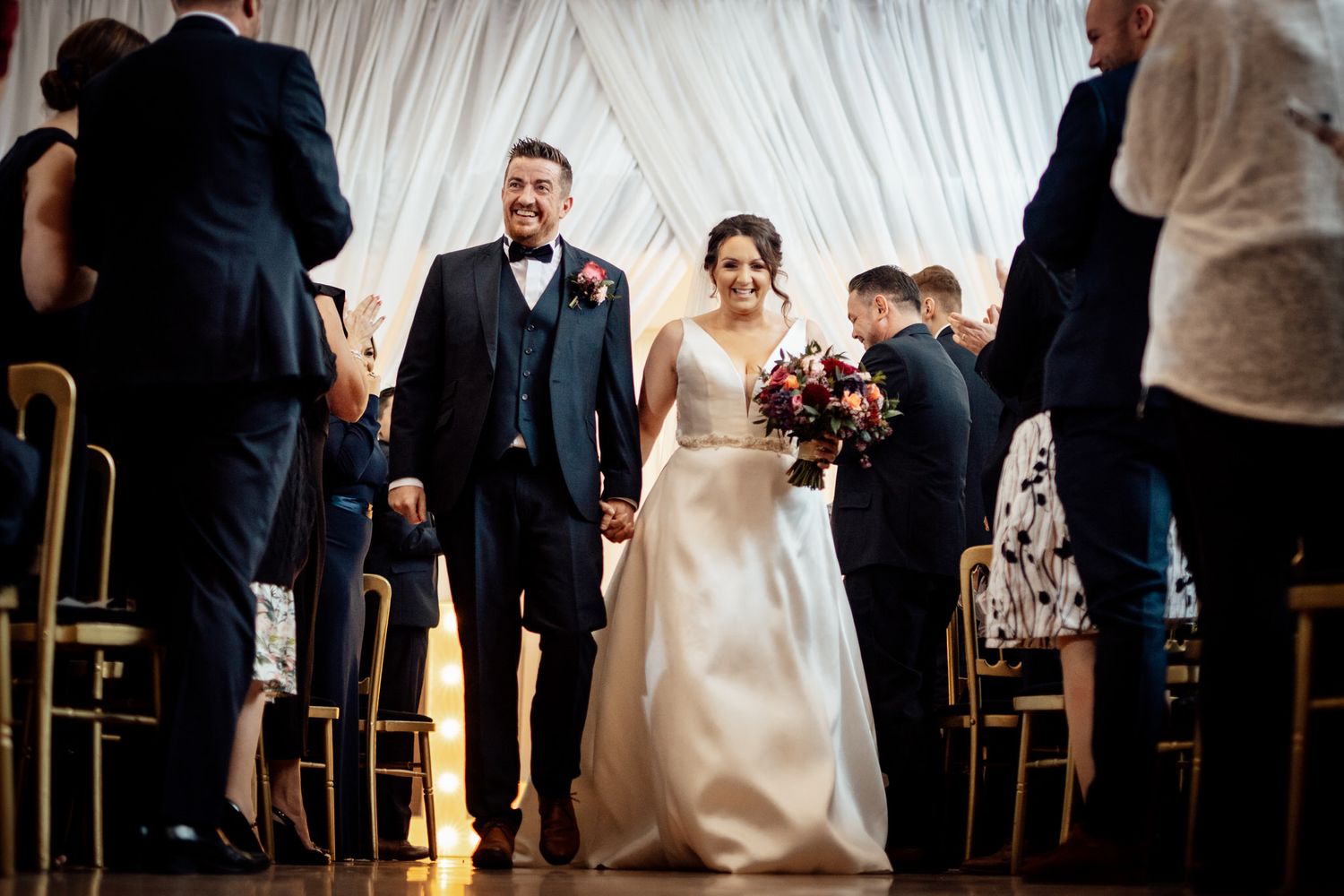 Wedding reception scene with guests mingling in an elegantly decorated venue.