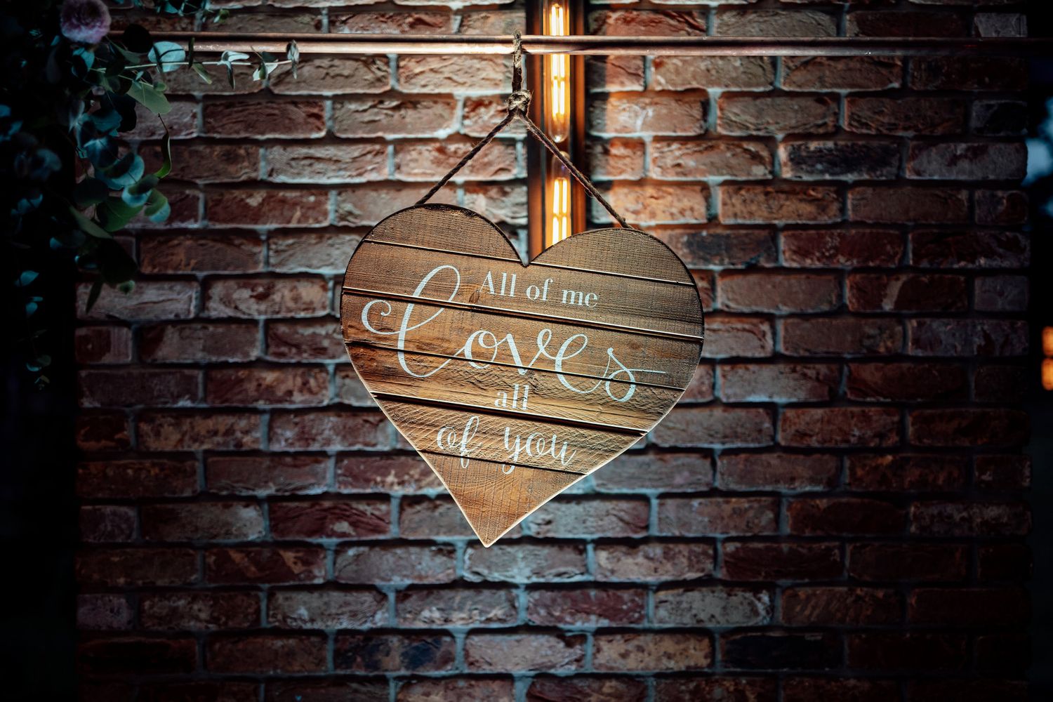 Rustic brick wall with romantic wooden signs and lighting for wedding decor.