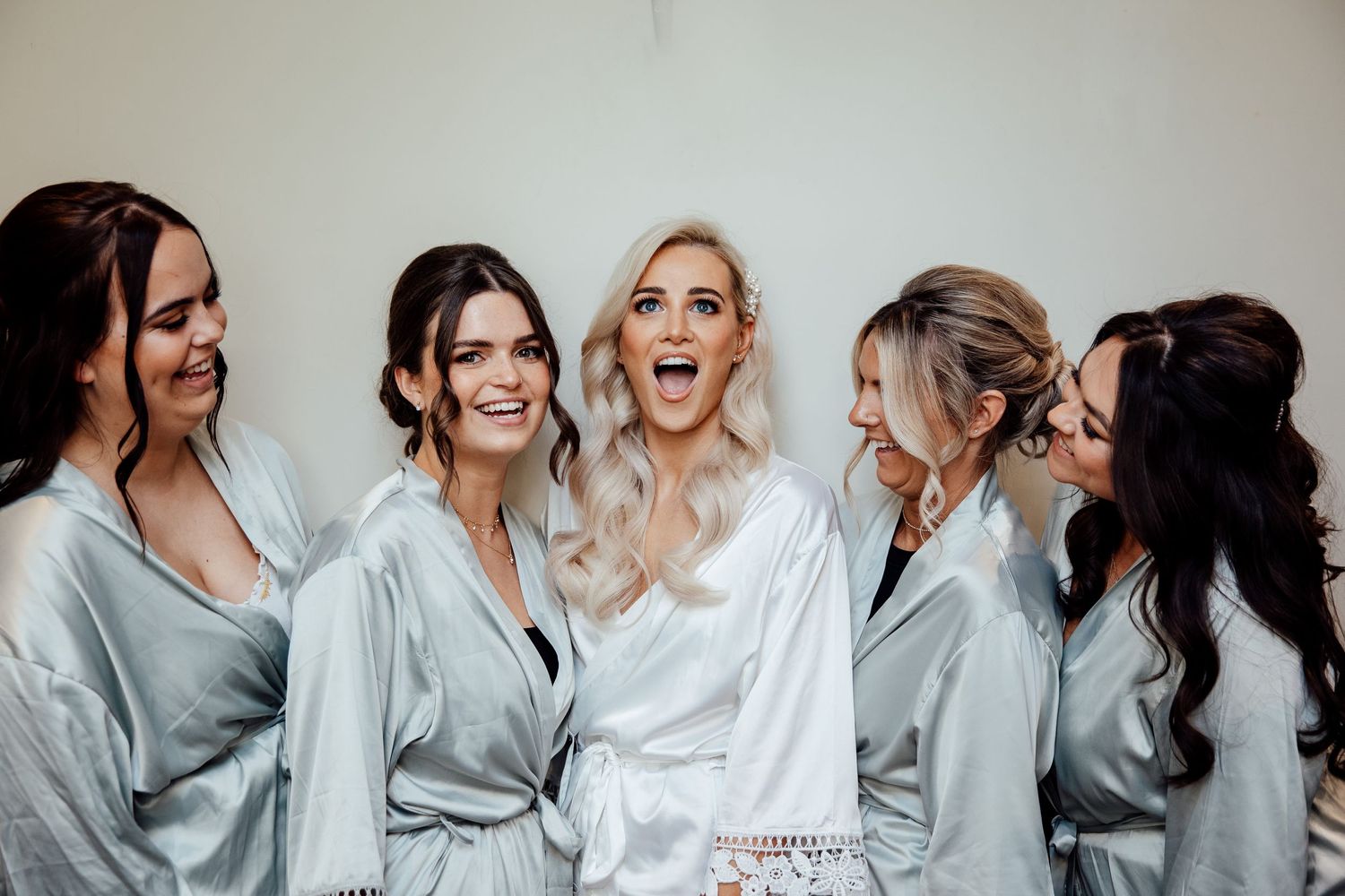 Bridal party members in matching gray robes pose together before the ceremony.