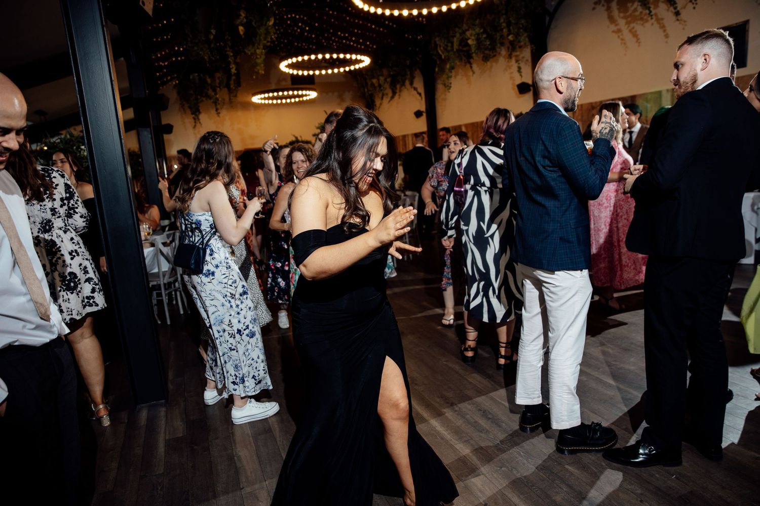 Wedding reception dance floor with string lights and celebrating guests.