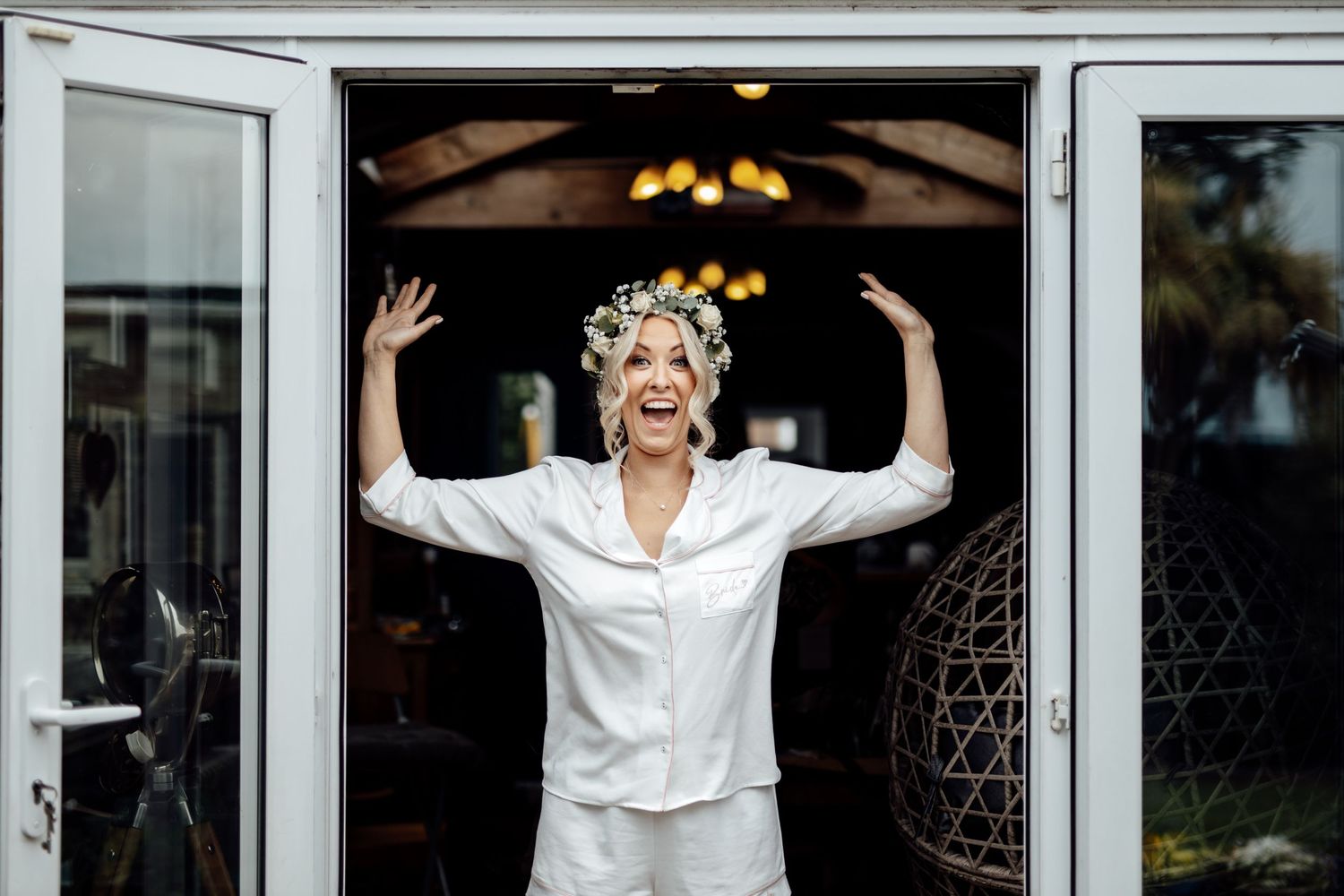 Person in white shirt raises arms joyfully through glass doors.