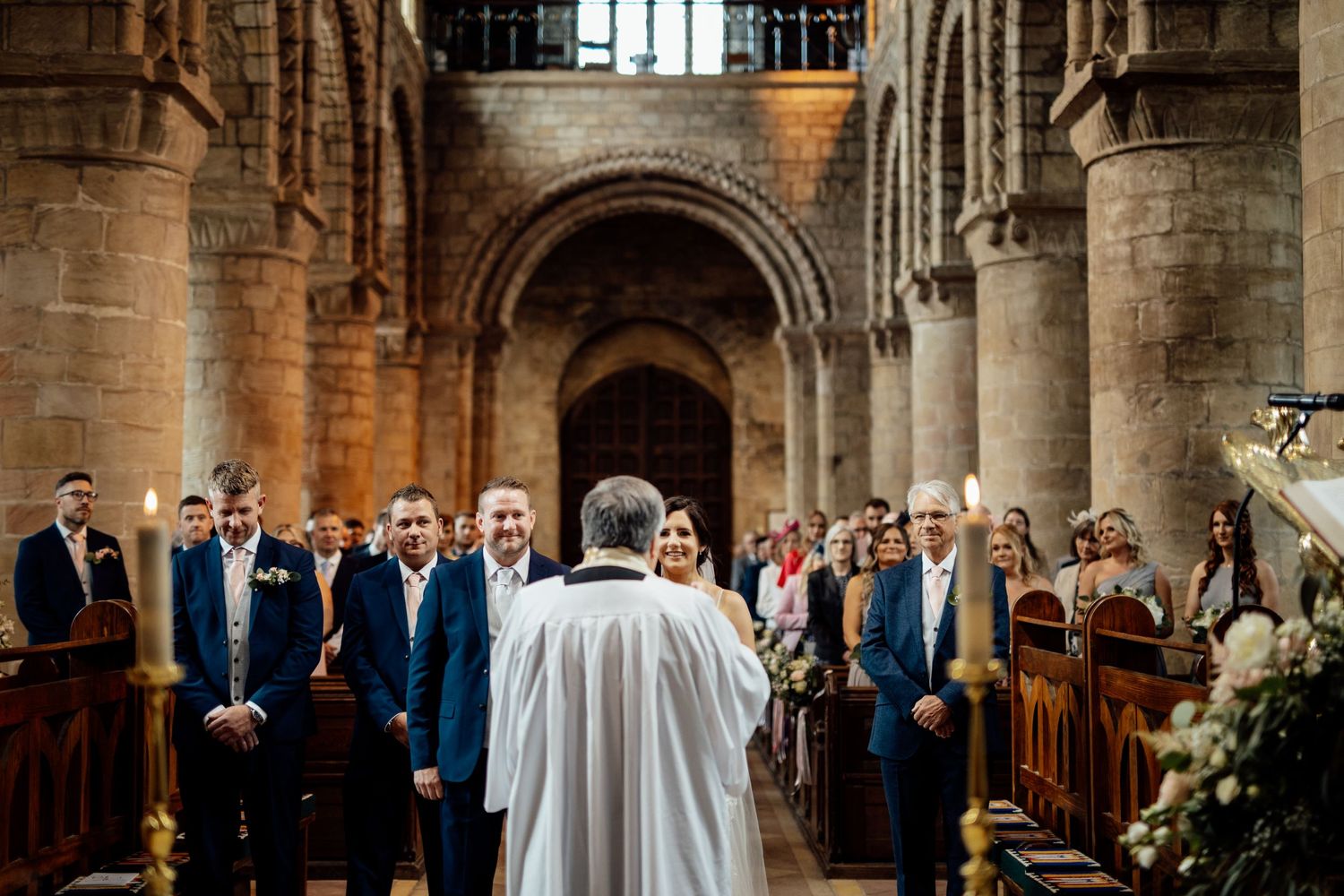 Wedding ceremony in progress inside a grand historic church with stone columns.
