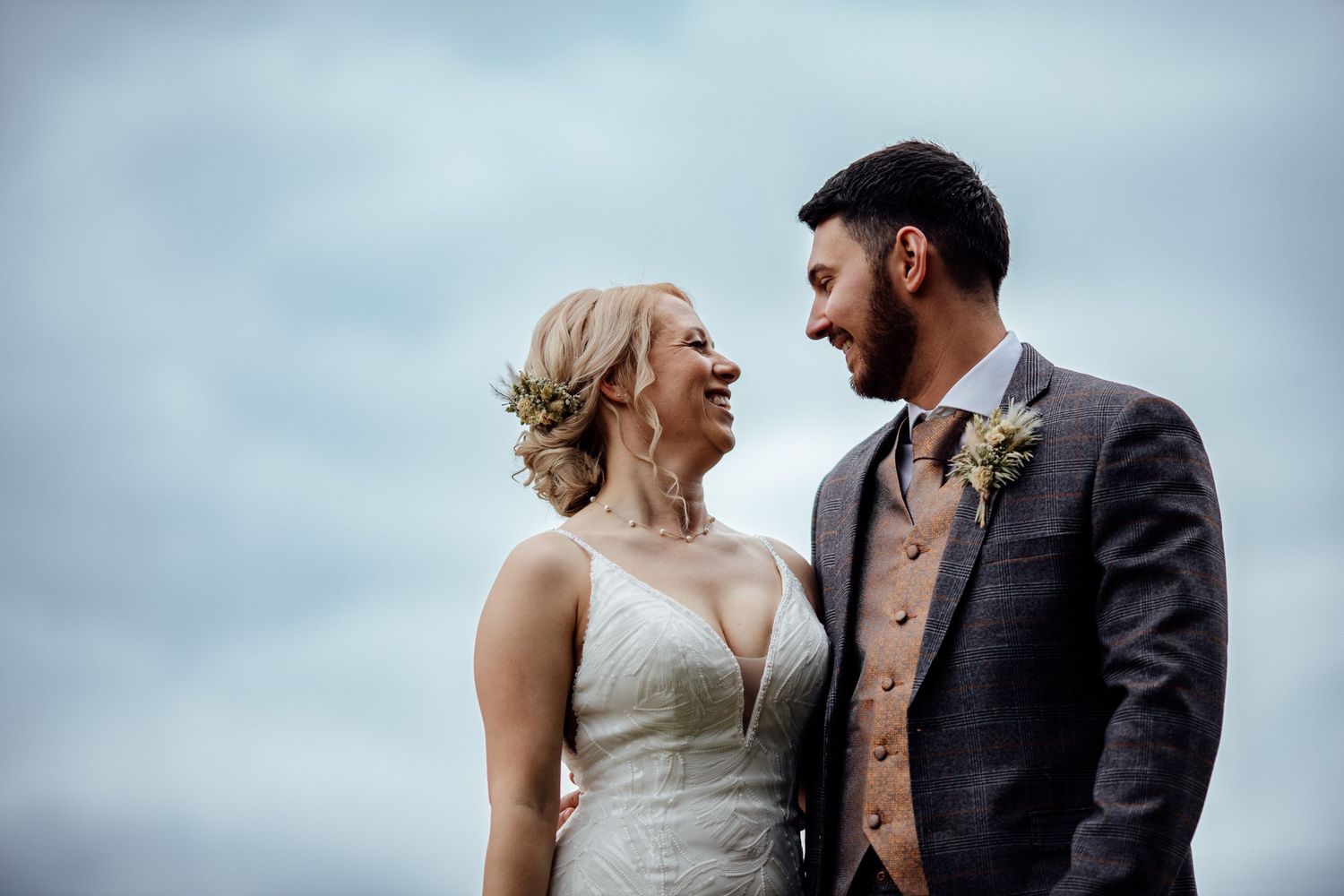 A couple shares a romantic moment against a cloudy sky backdrop.