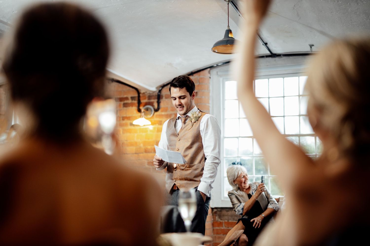 Wedding reception in a rustic industrial venue with exposed brick walls and pendant lighting.
