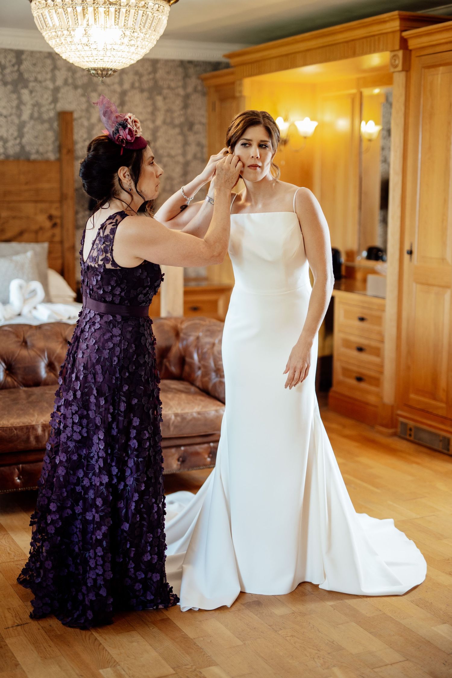 Wedding dress fitting scene with purple bridesmaid dress in elegant room with chandelier.