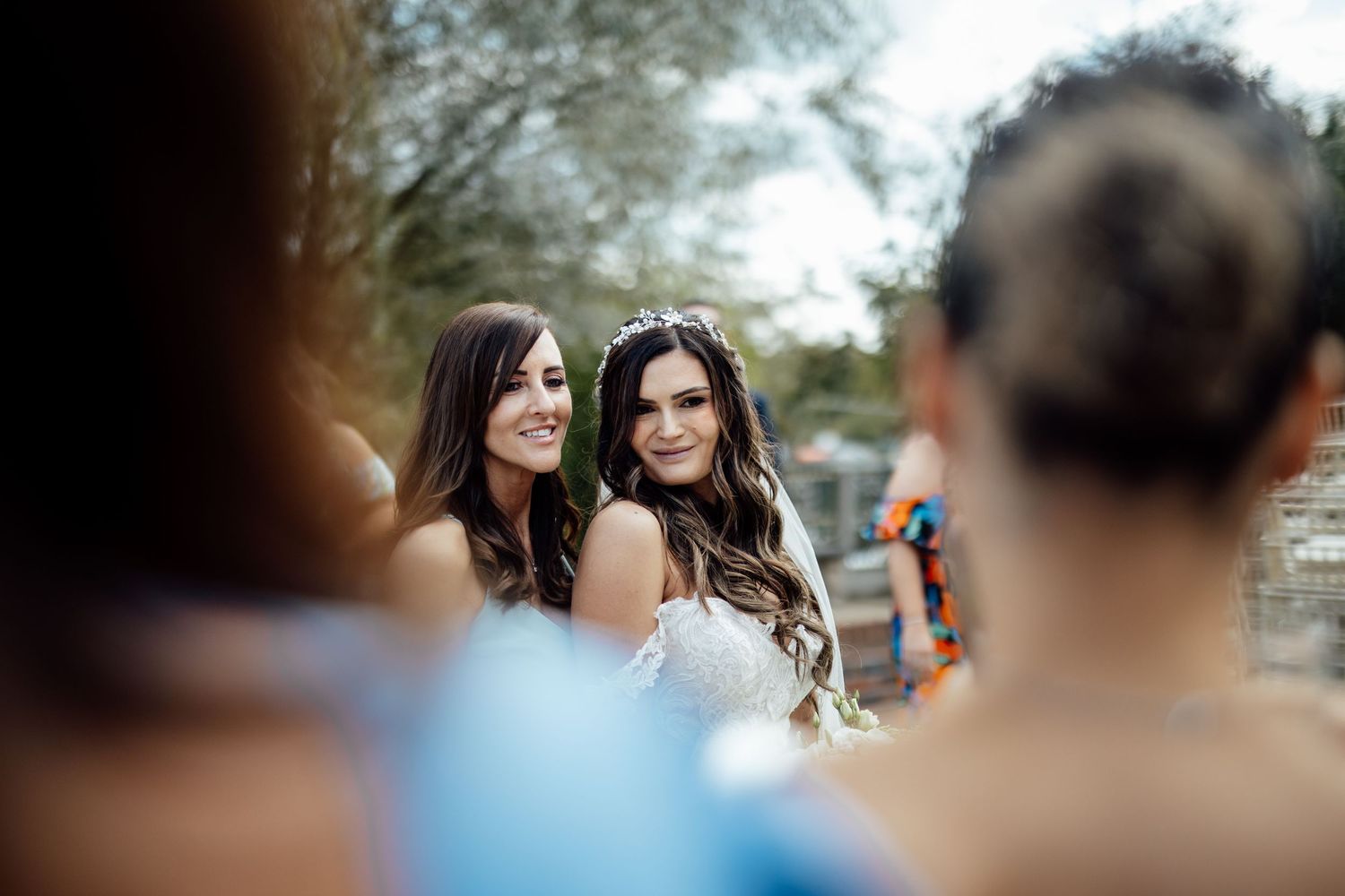 Wedding party poses together outdoors with bridesmaids in elegant black dresses.